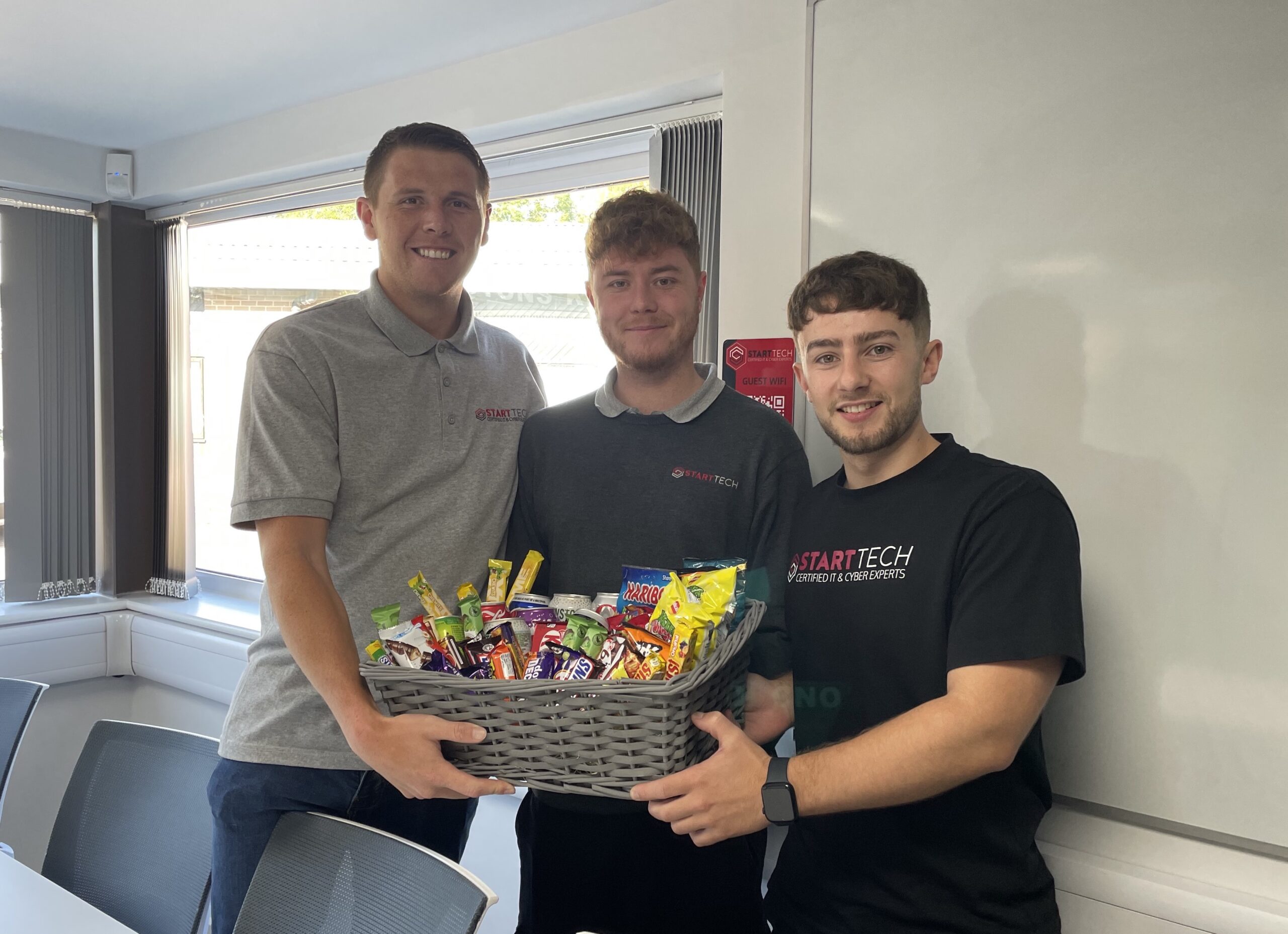 Three members of the Start Tech team holding a basket of snacks